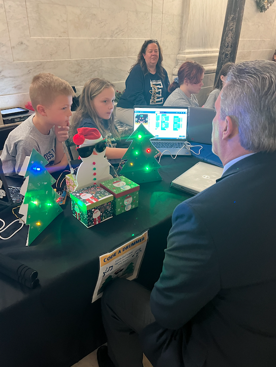 Student demonstrating a lit-up Christmas tree robot